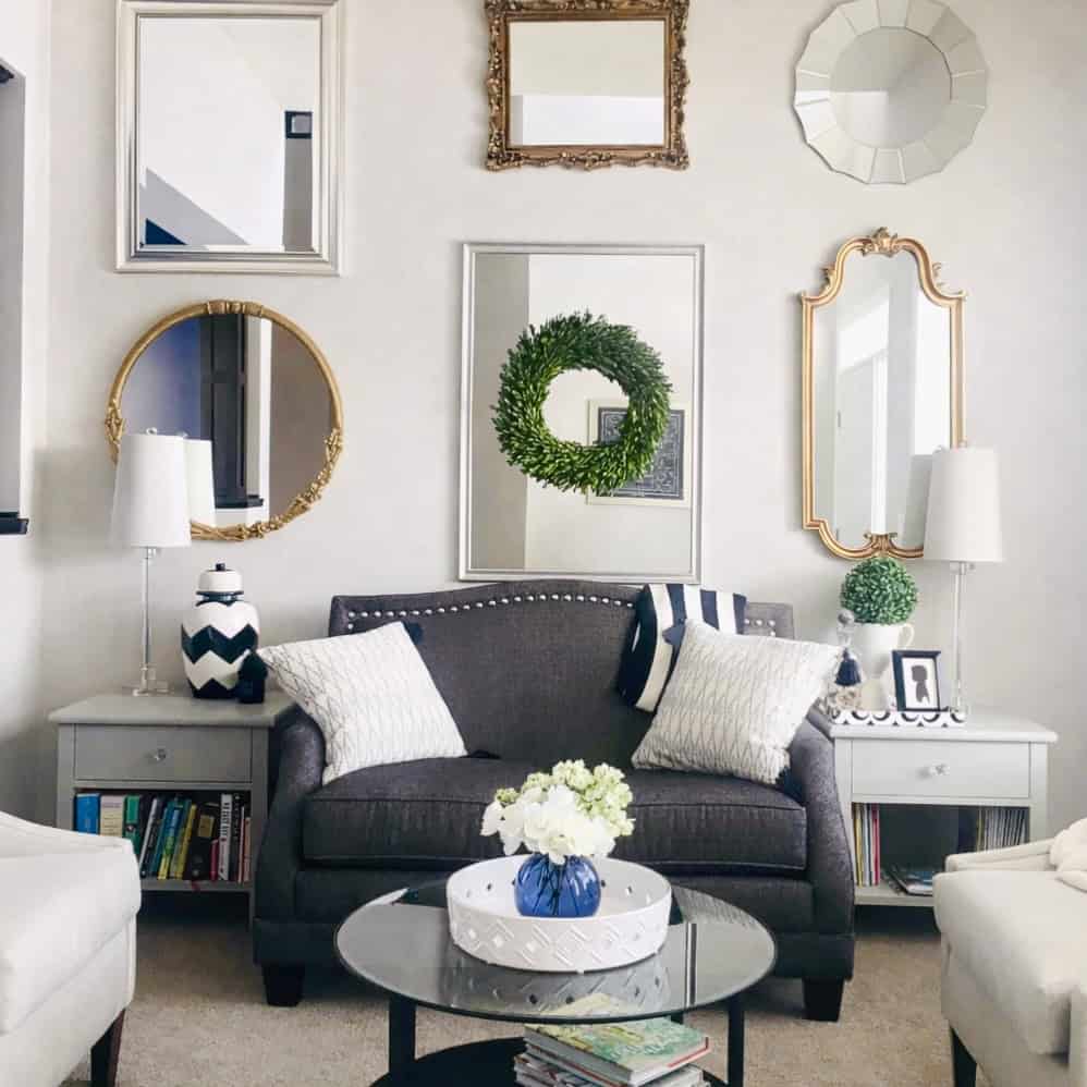 A cozy living room with decorative mirrors, a dark sofa, and stylish accents.