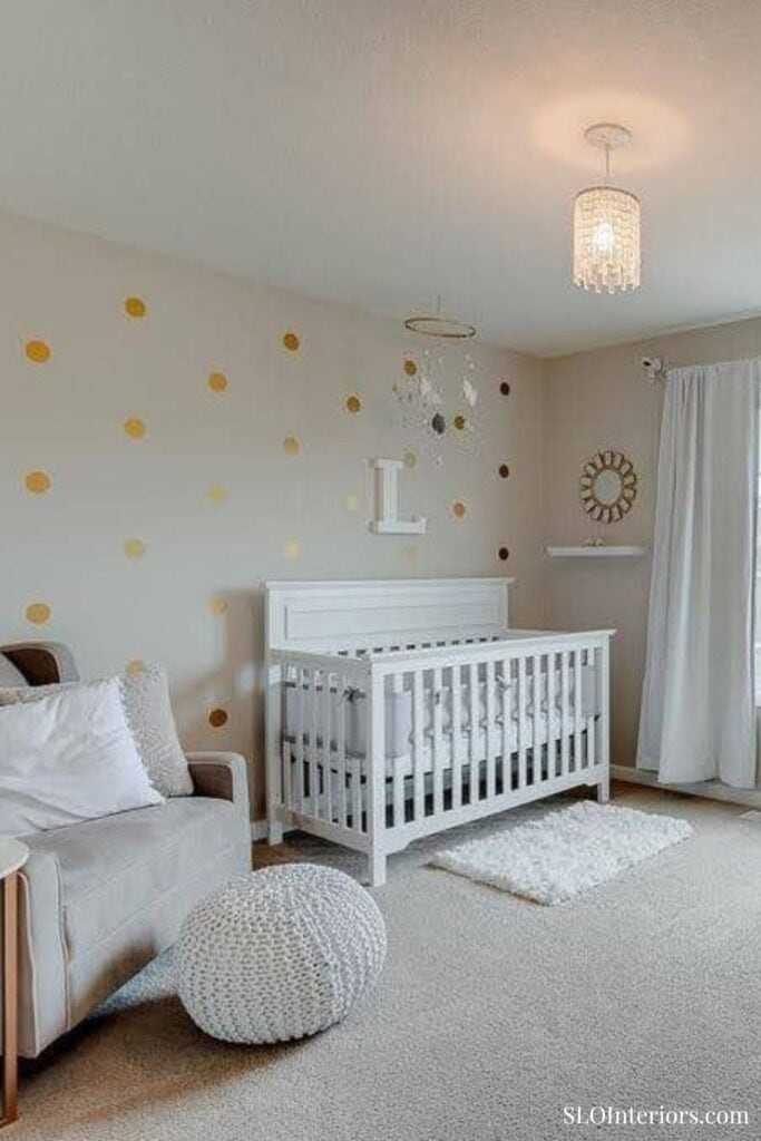 A baby crib in a modern nursery with white walls, gold polka dots, and cozy decor.
