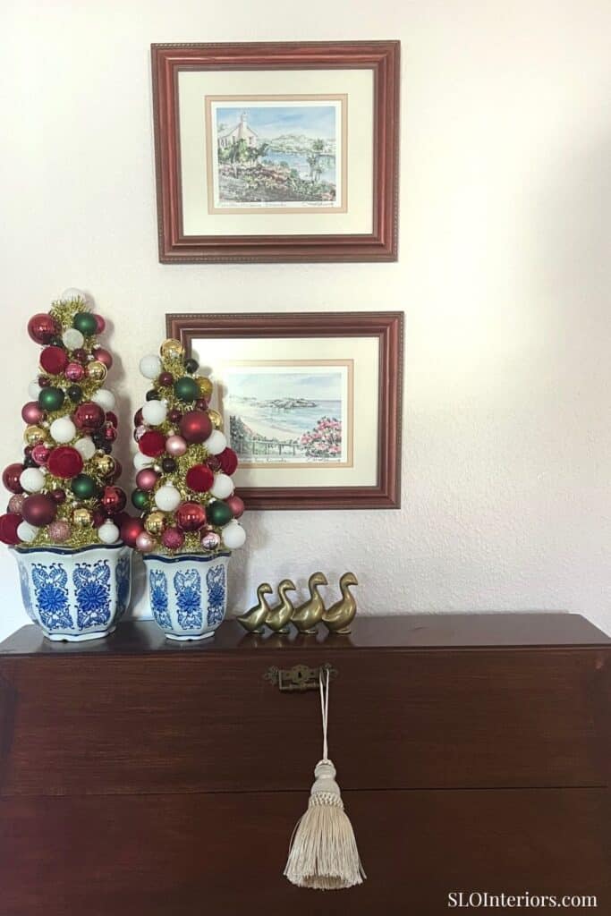 Festive holiday decor with Christmas trees and framed artwork on wall.