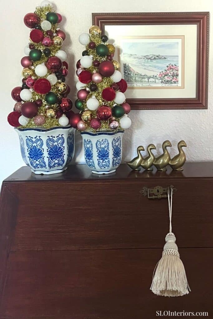 Festive Christmas trees with ornaments in blue and white planters, wall art, and decorative ducks.