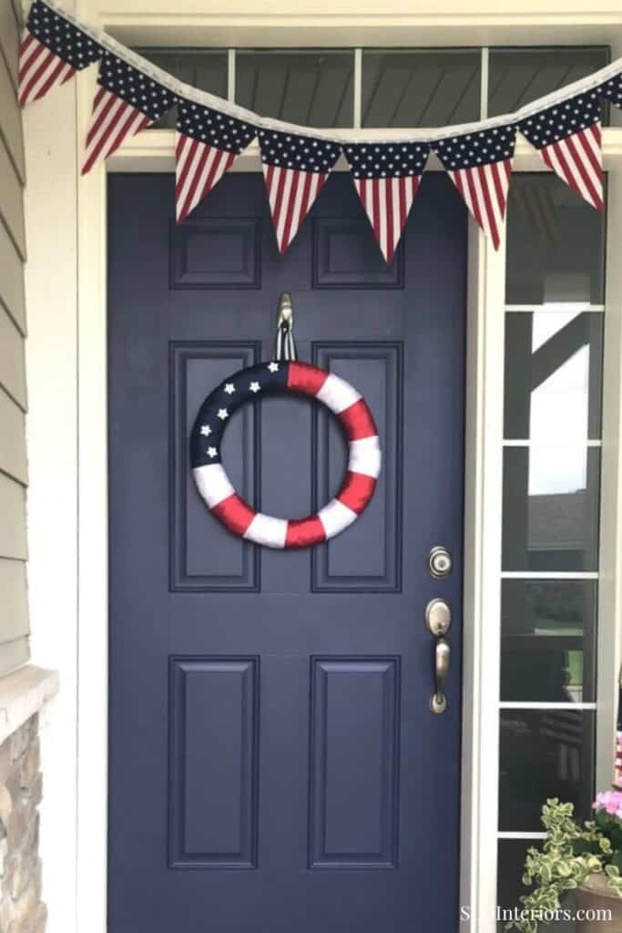 Patriotic front door decorated with American flags and a wreath for Independence Day.