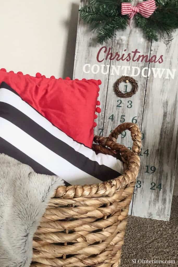 A cozy Christmas corner with pillows and a countdown calendar in a woven basket.