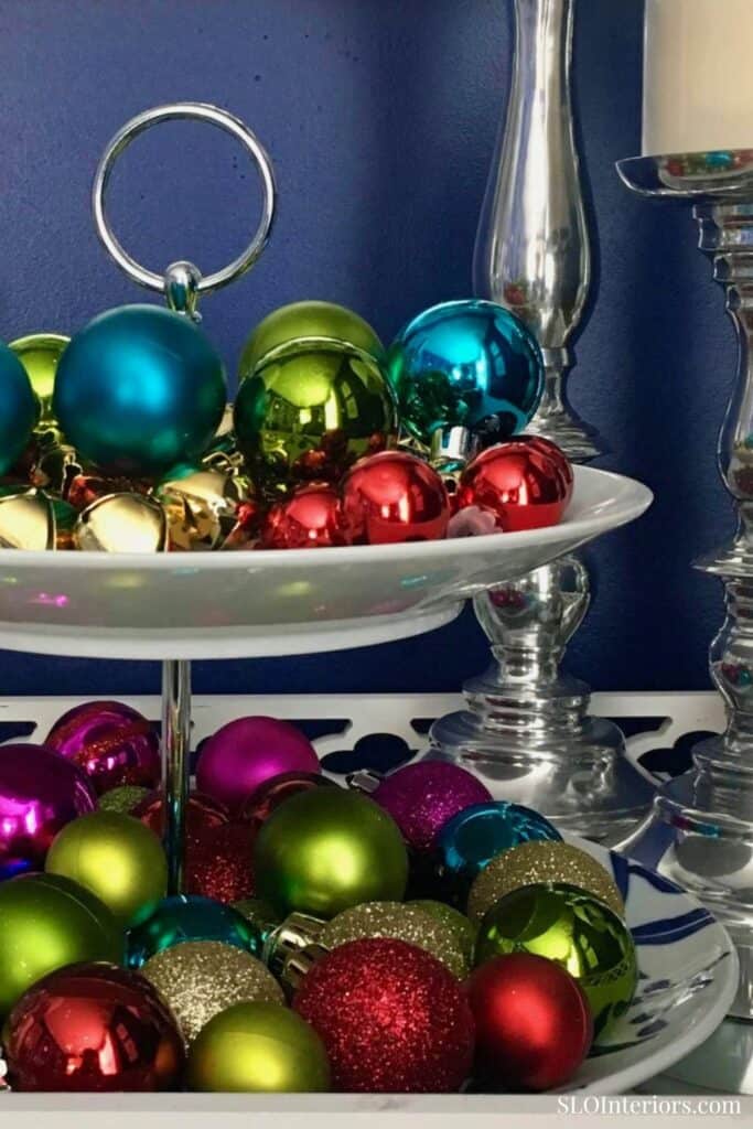 Festive Christmas ornaments in vibrant colors on a decorative display shelf.