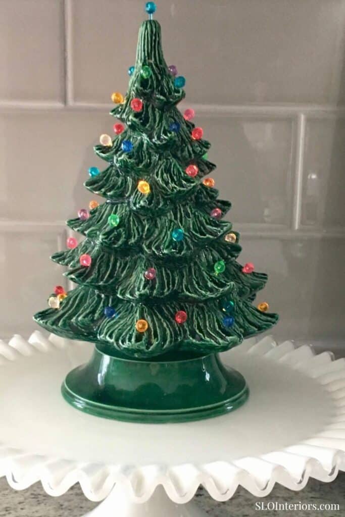 Festive ceramic Christmas tree with colorful ornaments on a white decorative plate.