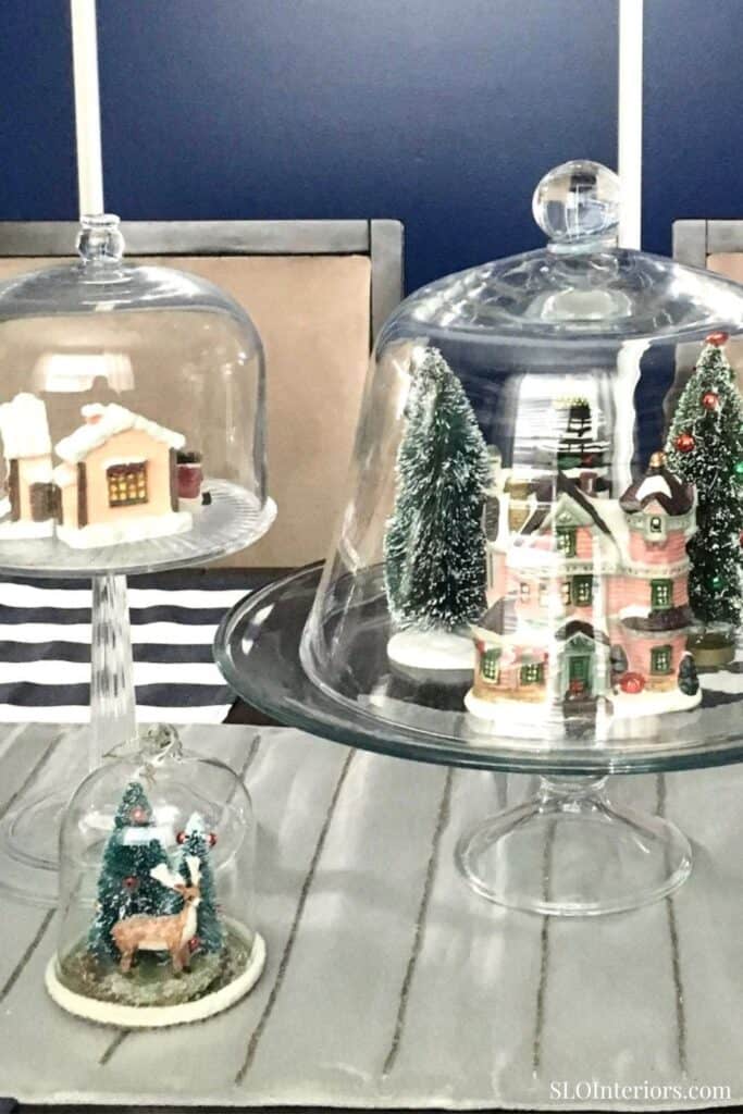 Festive holiday miniature houses and Christmas trees under glass domes for home decor.