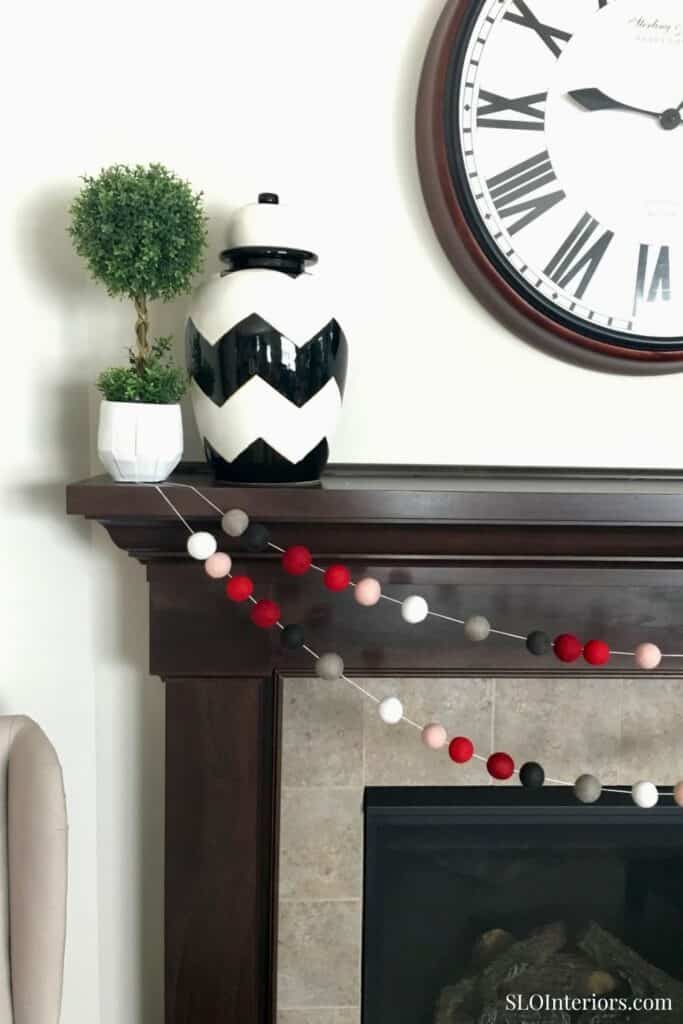 Modern fireplace mantel with decorative vases, clock, and garland in stylish home decor.