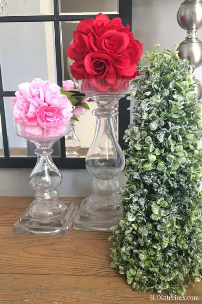Elegant floral arrangements with pink and red roses, decorative glass vases, and greenery for interi.