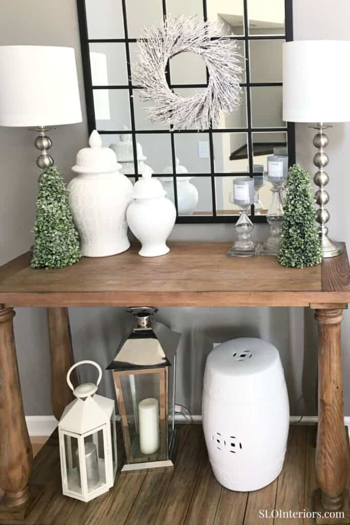 Elegant holiday decor with white and green accents on wooden console table.