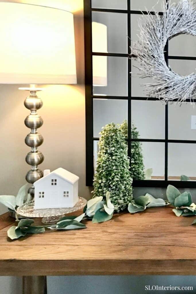 Modern interior decor with a table lamp, greenery, and decorative wreath for home styling.