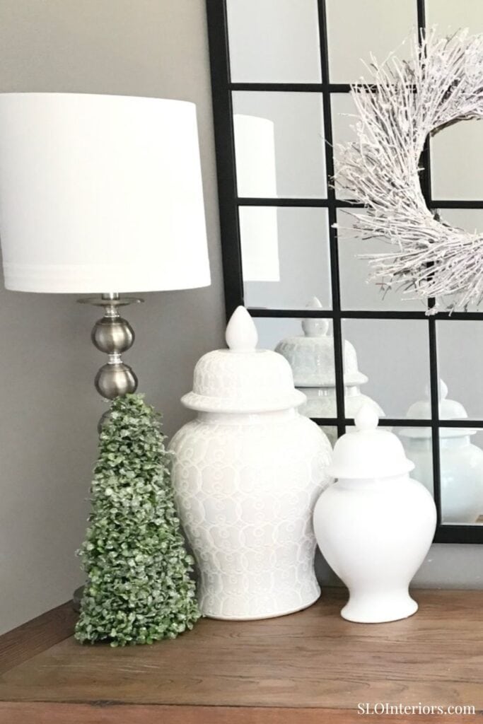 Elegant white decorative vases with greenery and modern wall art for interior design.