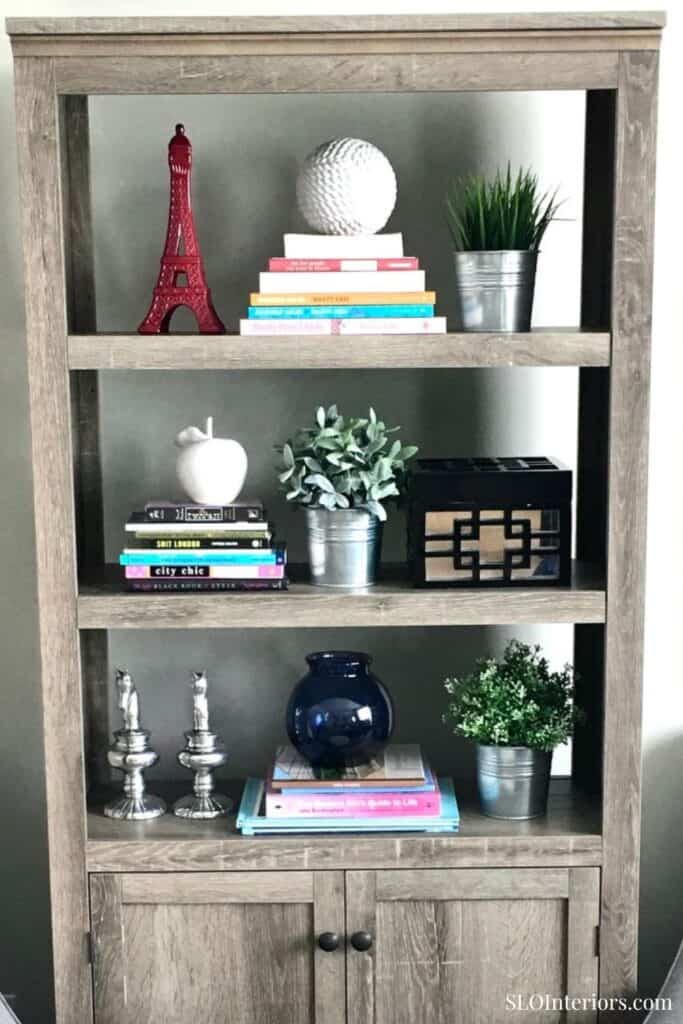 Eiffel Tower decor, books, and plants on wooden bookshelf for stylish interior design.
