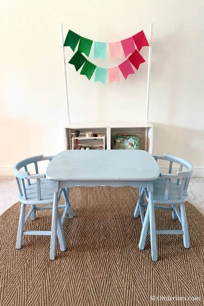 A colorful children's play table with two chairs and festive bunting decorations.