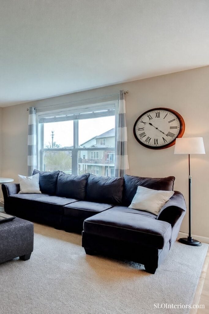 A cozy living room with a dark gray sectional sofa, large window, and modern decor.