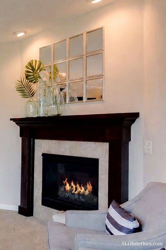 Modern living room with fireplace, decorative mirror, and cozy armchair.