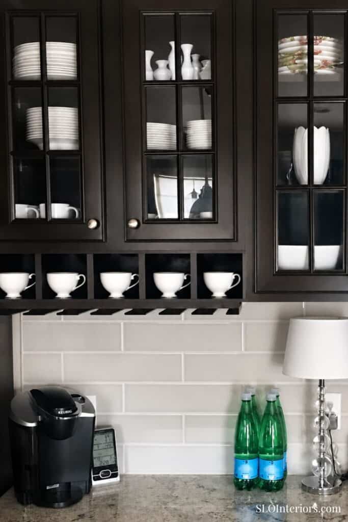 Elegant black kitchen cabinets with glass doors displaying white dishware and glassware.