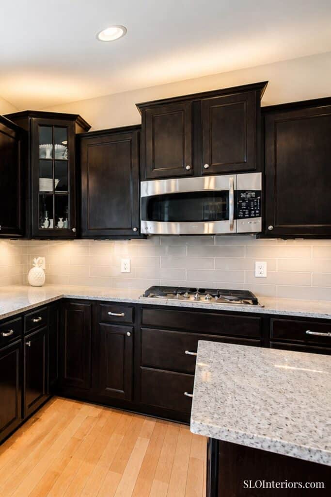Modern black kitchen cabinets with stainless steel microwave and granite countertops.