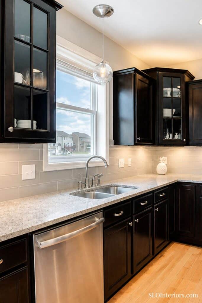 Modern black kitchen cabinets with granite countertop and stainless steel sink.