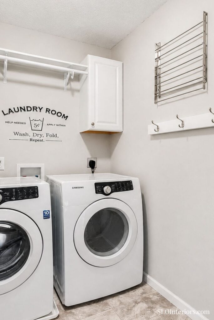 Washer and dryer in a modern laundry room with wall-mounted storage and hooks.