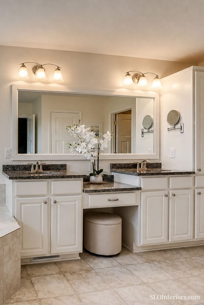 Elegant bathroom vanity with white cabinetry, granite countertops, and floral decor.