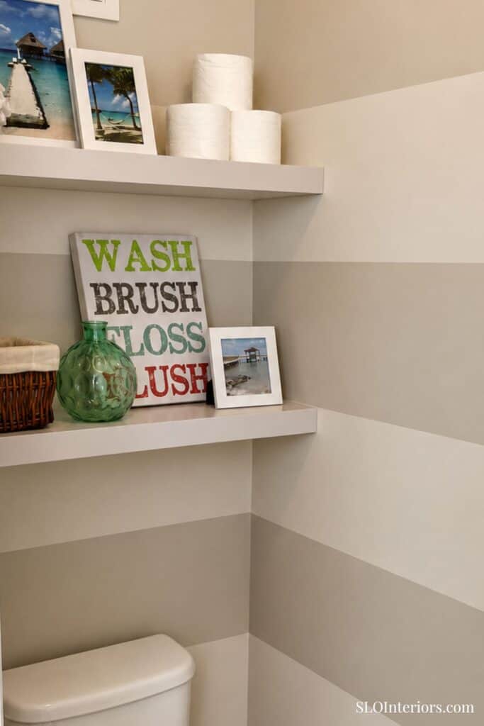 Washi brush, floss, and decorative items on white shelves in modern bathroom corner.