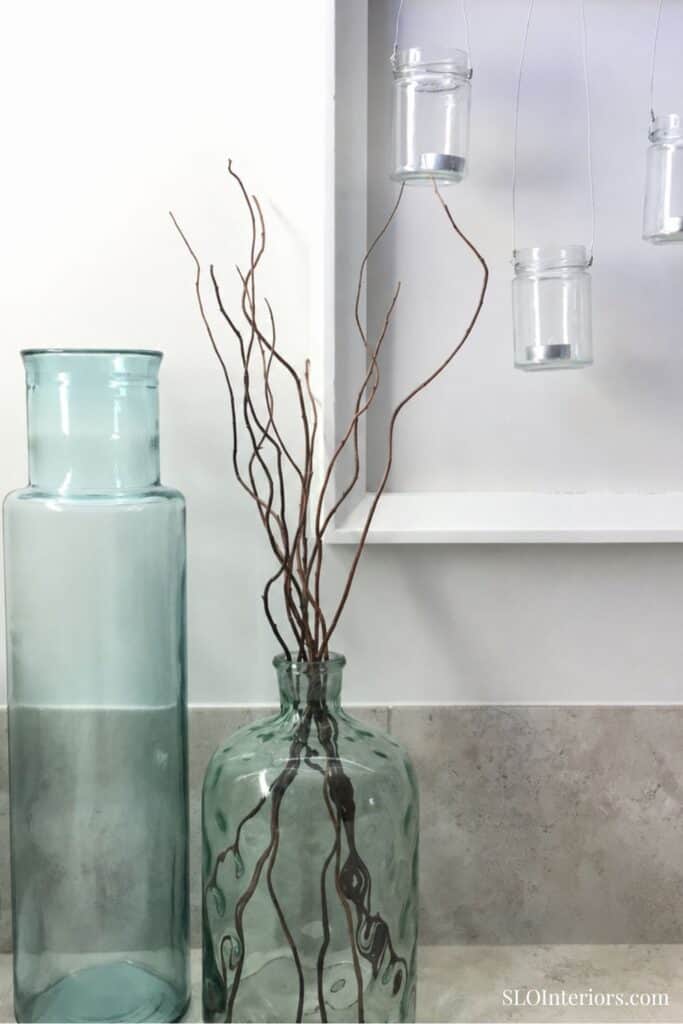 A lush glass vase with decorative twigs and hanging jars for modern interior decor.