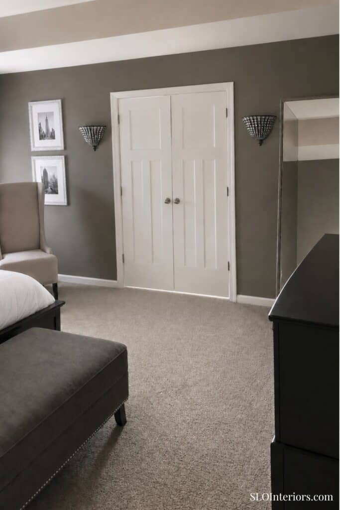 Modern bedroom with gray walls, white double doors, and stylish wall sconces.