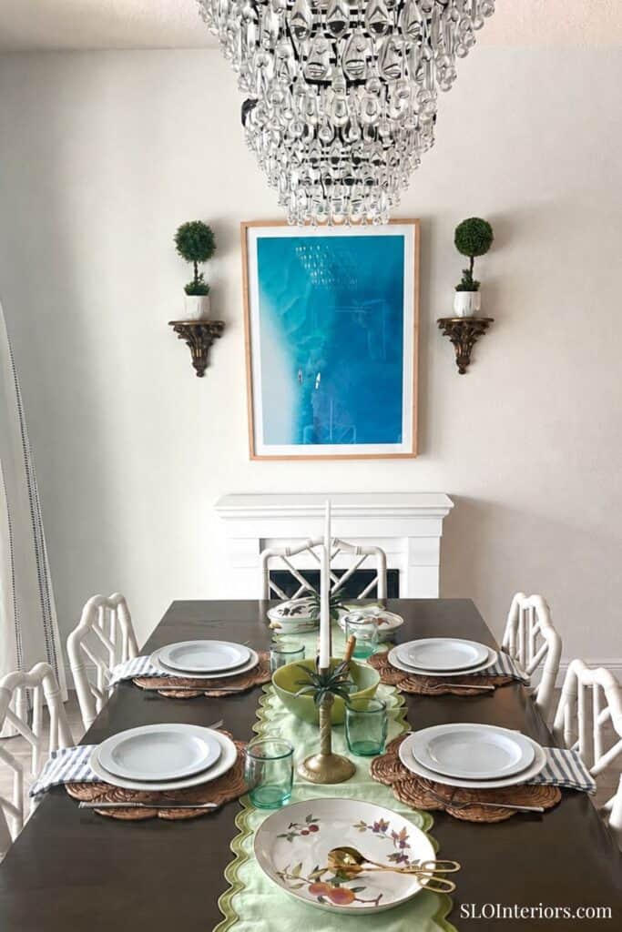Elegant dining room with chandelier, white walls, and a dark wood table set for six.