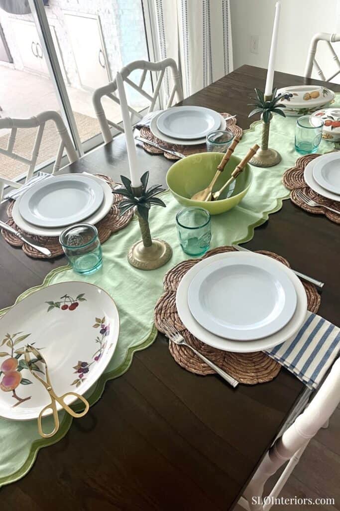 Elegant dining table setup with white plates, green bowls, and decorative candles.