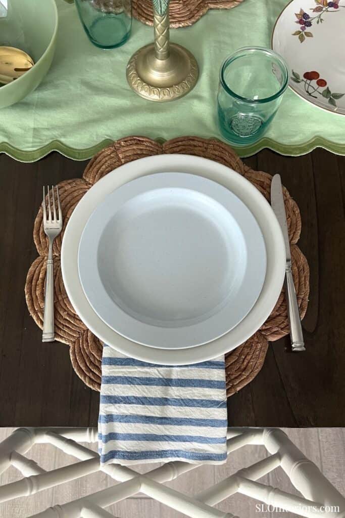 Elegant table setting with white plate, cutlery, and glassware on a wooden table.