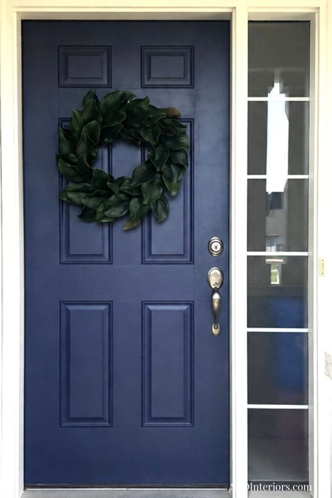 Front door with a decorative wreath and glass side panel in a home entrance.