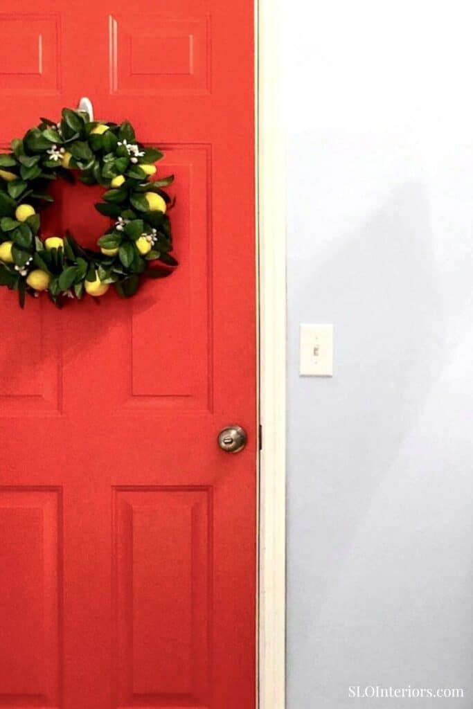 Decorative holiday wreath on a red door in a modern home interior.