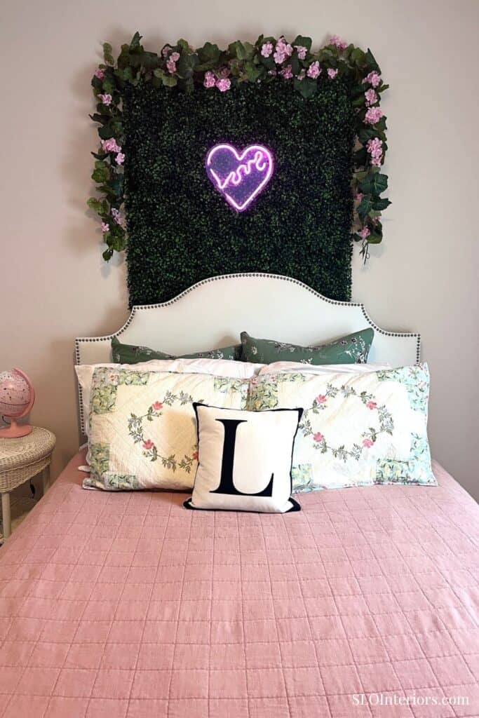 Decorative bedroom with floral pillows and neon heart wall art.