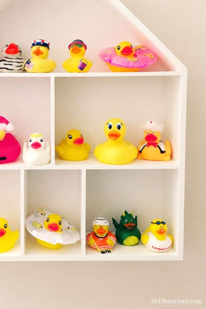 Colorful rubber ducks and bath toys on white shelves for kids' bathroom decor.