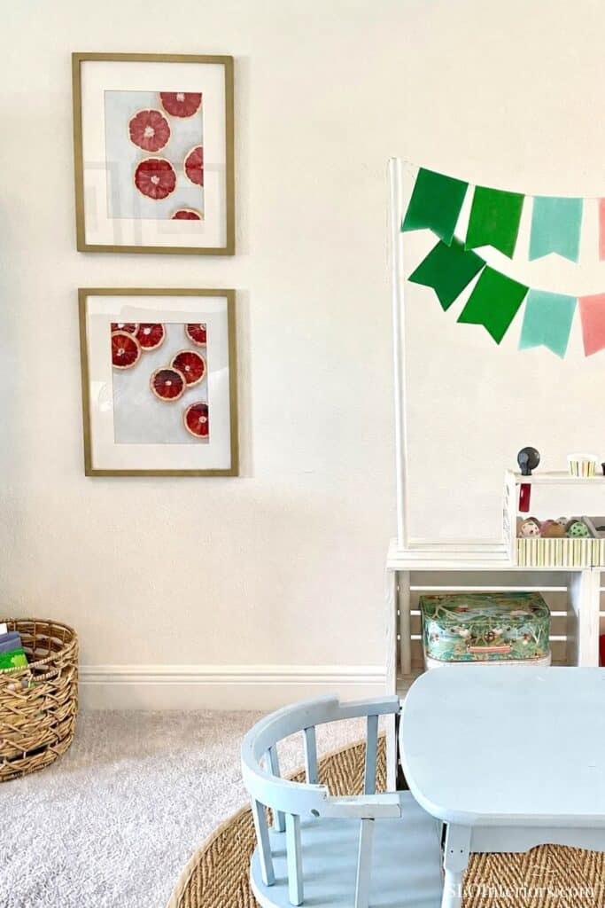 Child's playroom with framed art, colorful bunting, and a light blue table.