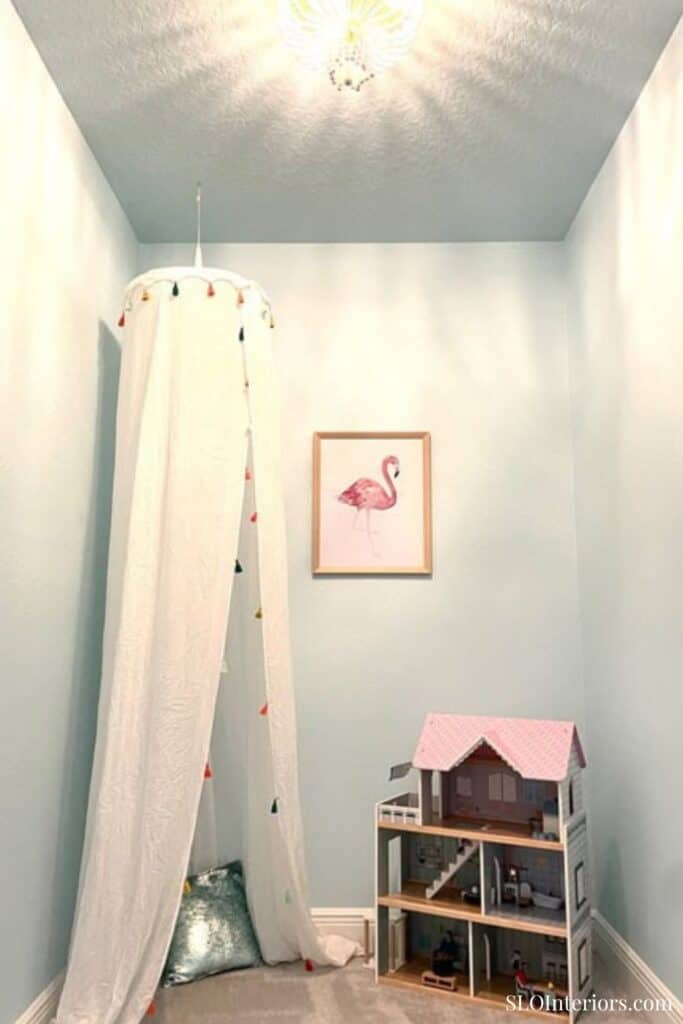 Children's playroom with a dollhouse, flamingo art, and cozy decor.