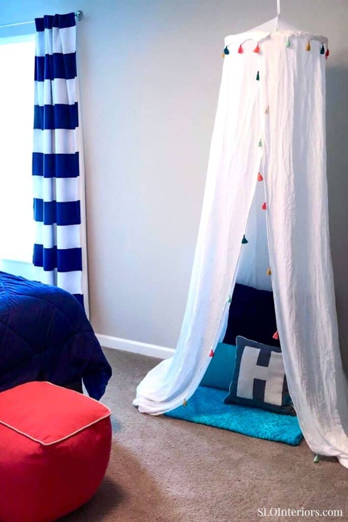 Children's indoor play tent with colorful flags and cozy cushions in a modern room.