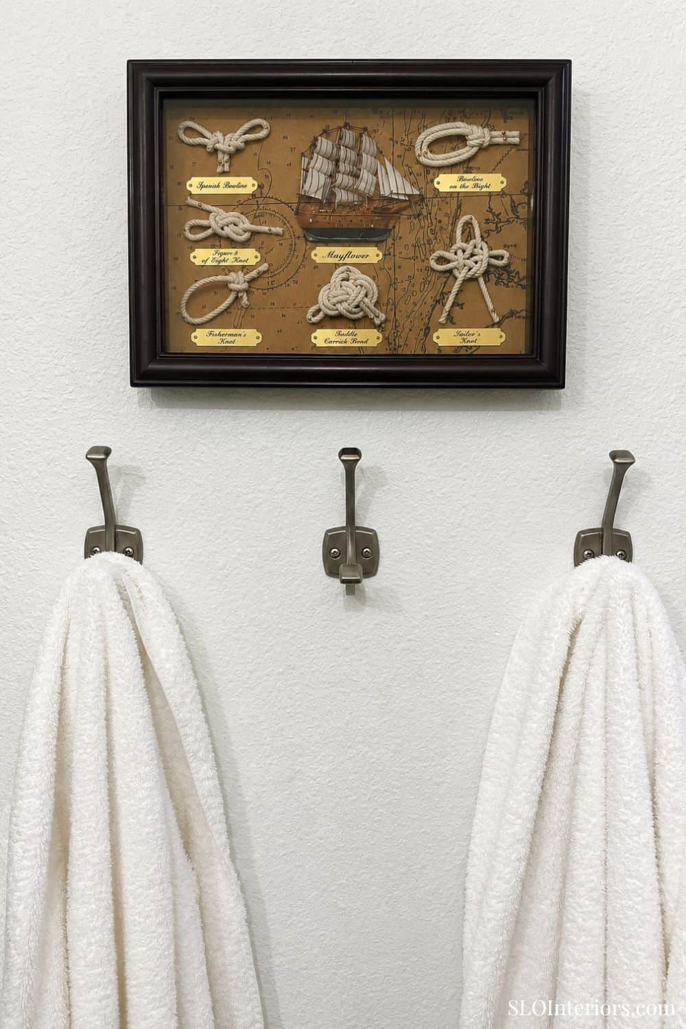 Nautical knot display with a ship model and rope knots in a shadow box frame.
