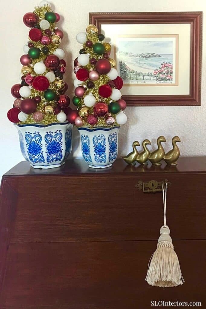 Festive Christmas trees with ornaments in blue and white pots on a wooden surface.