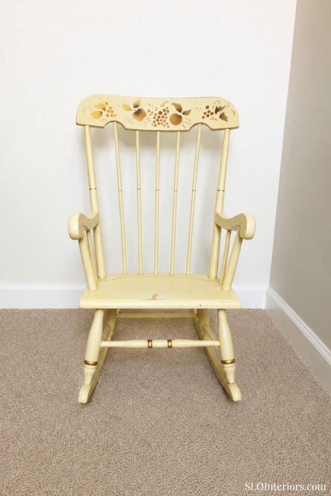 Vintage yellow wooden rocking chair with floral cutout design on backrest.