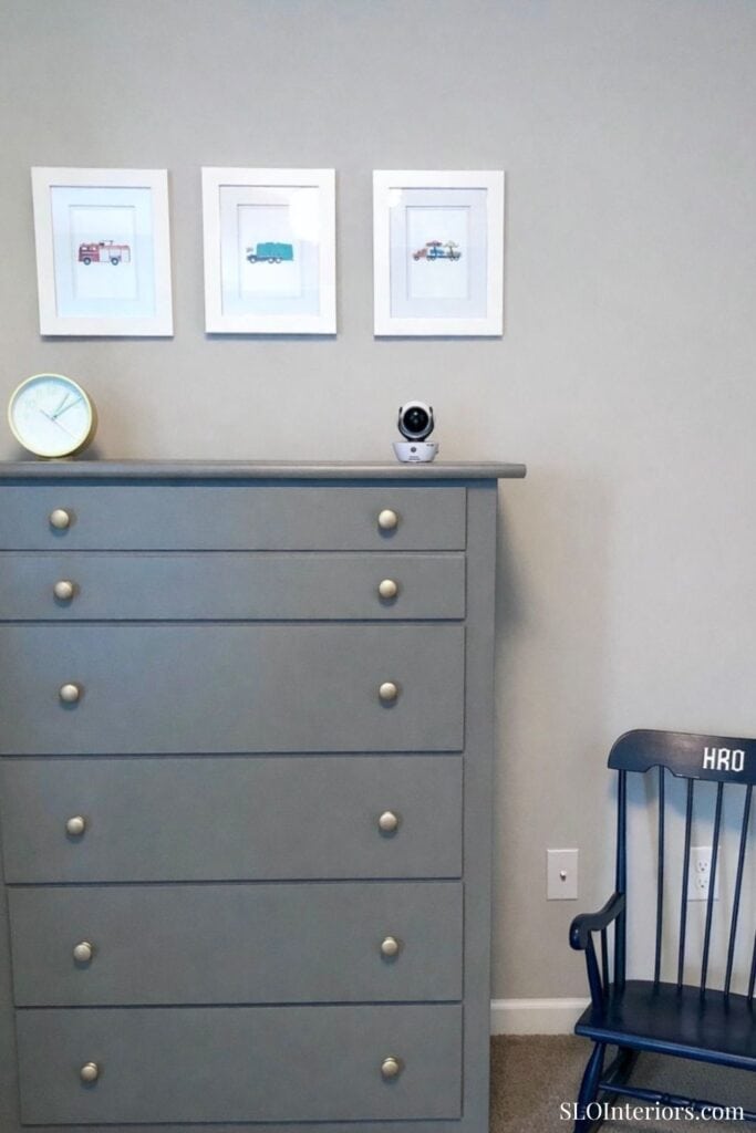 Modern gray dresser with framed car art and a black chair in a stylish room.
