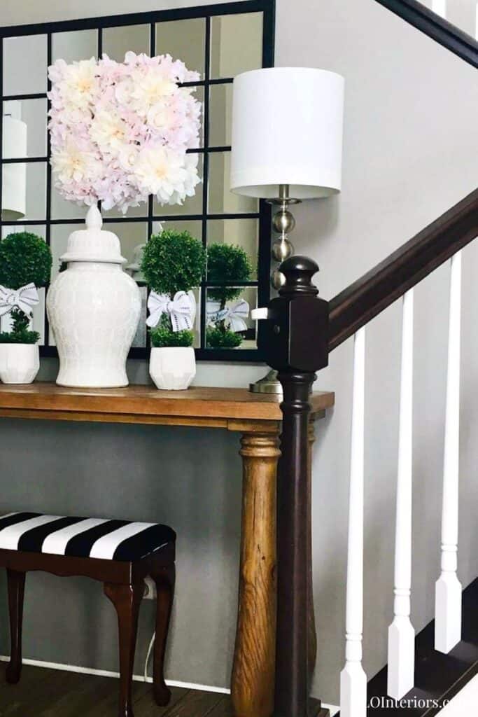 Elegant entryway with floral decor, table lamp, and black-and-white striped bench.