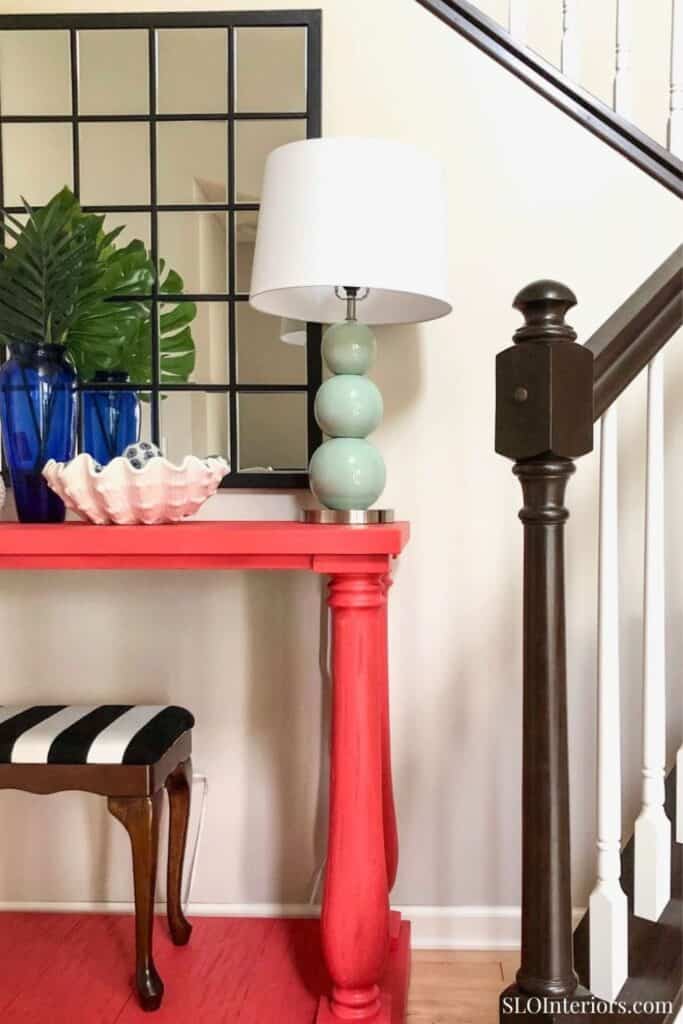 Decorative table with lamp, plants, and mirror in modern interior design.