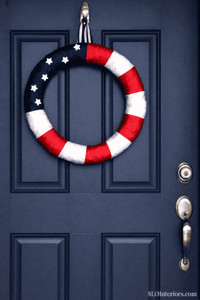 Patriotic door wreath with stars and stripes on a navy blue door.