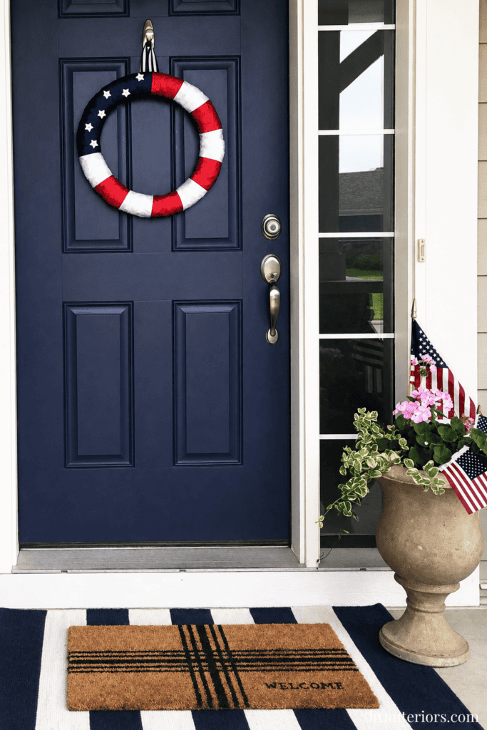 Patriotic door decor with American flag wreath and welcome mat.