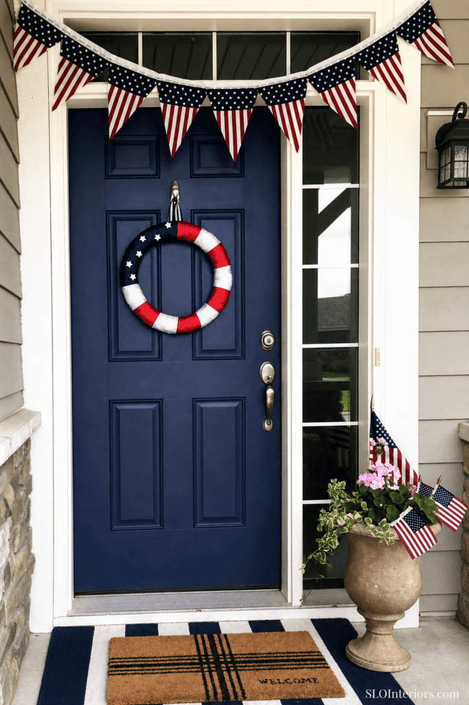 Patriotic front door decorated for Independence Day with American flags and wreath.