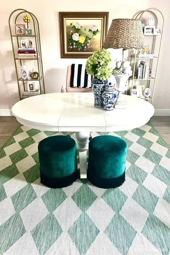 Elegant dining room with white table, green velvet stools, and floral decor.