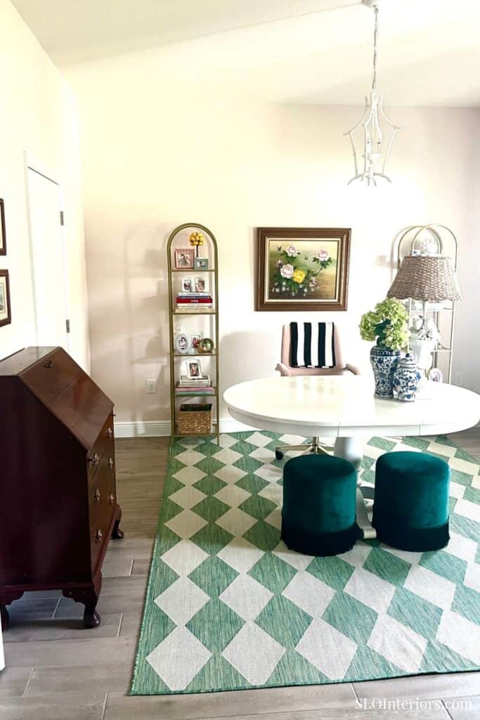 Elegant dining room with round table, teal stools, and floral decor.