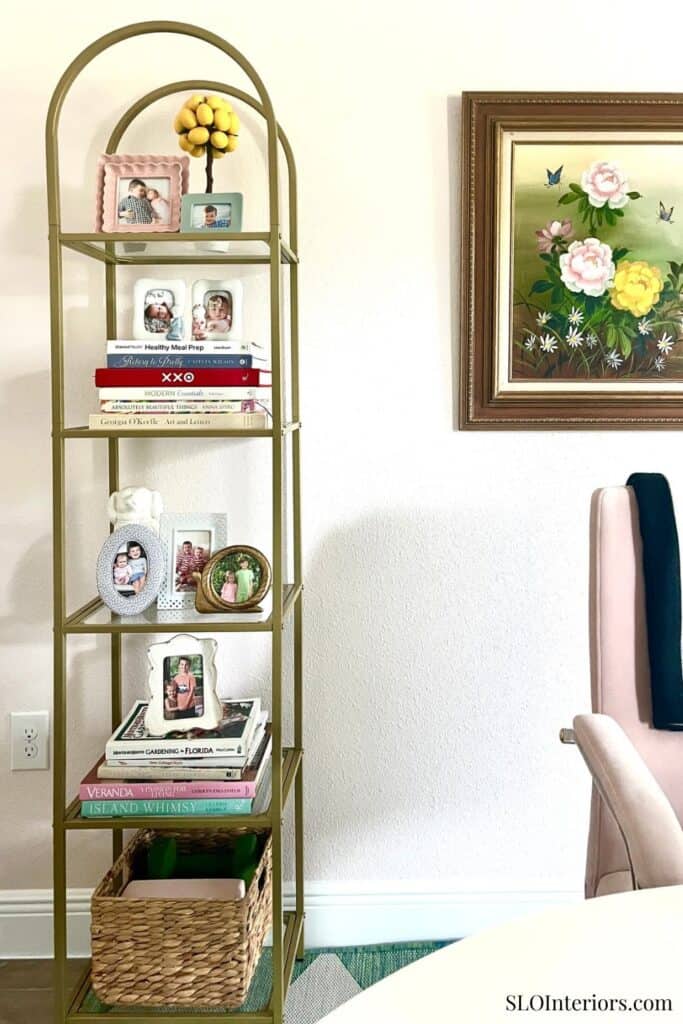 Decorative gold shelving unit with family photos and books in a cozy living room.