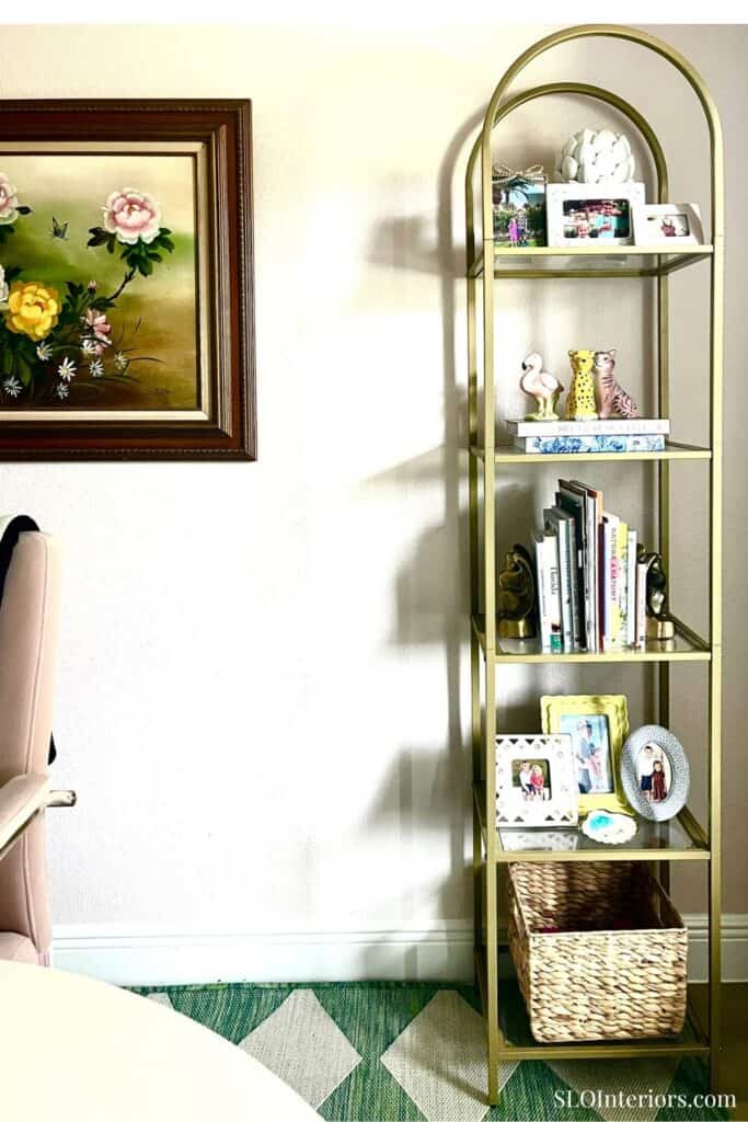 Gold arched bookshelf with decorative items and family photos in a cozy living room.