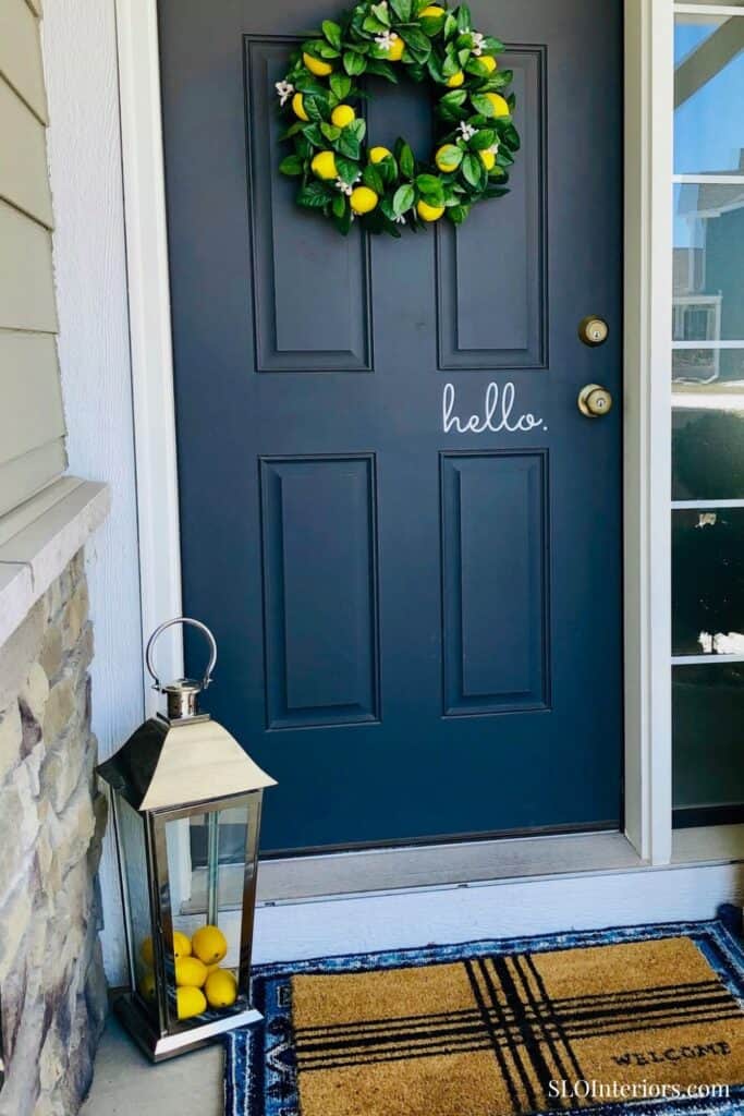Front door decorated with a lemon wreath and a lantern with yellow balls.